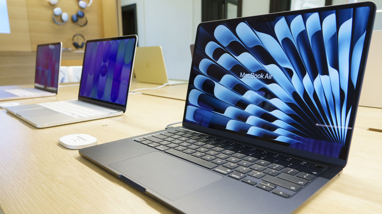 Three MacBooks on a table next to each other.