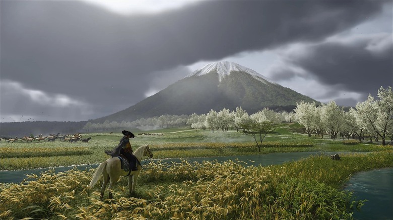 A person on horseback on an open plain by a river, with a snow-capped mountain in the distance.