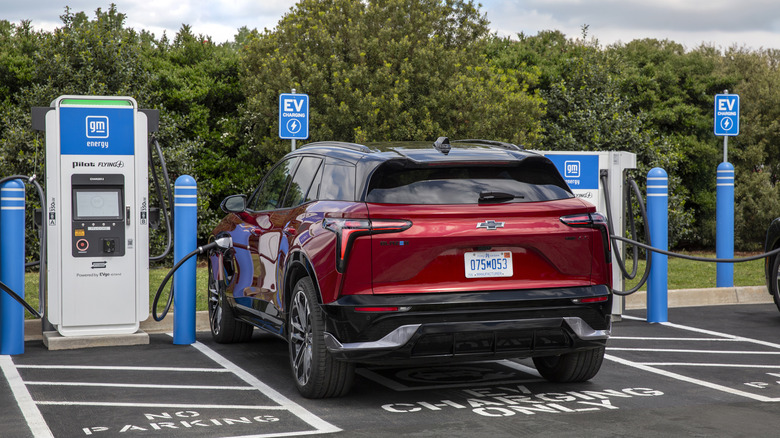 Photo of a red electric SUV plugged into a GM-branded charging station.