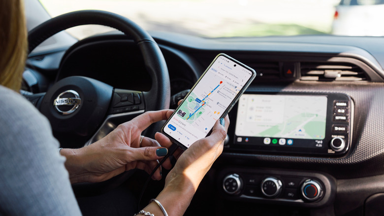 Woman in a car syncing Google Maps on their smartphone with their infotainment system.