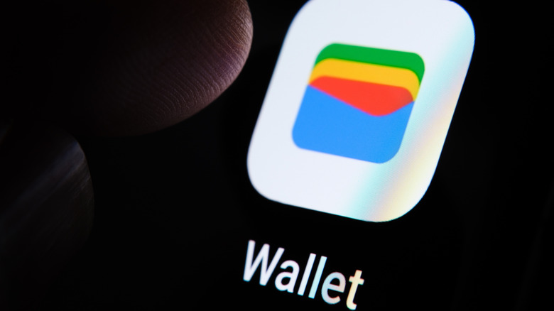 Google Wallet app on phone screen with finger hovering above it.
