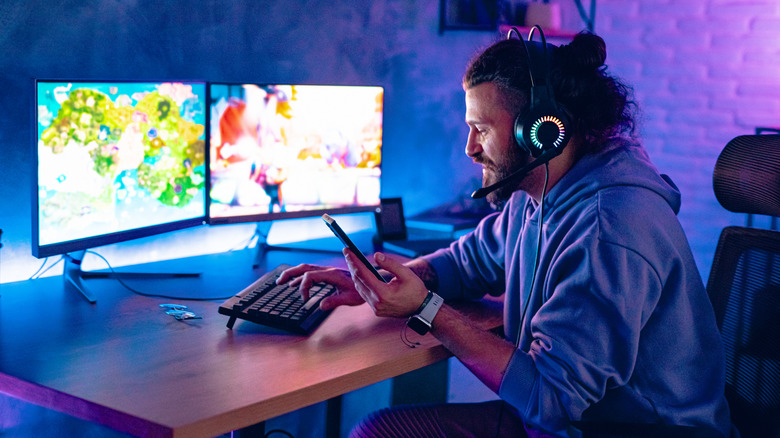Man using mobile phone while playing games on PC