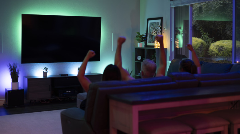 People on couch watching TV and cheering