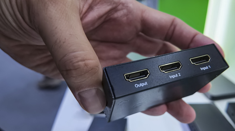 A small, simple HDMI switched in a hand.