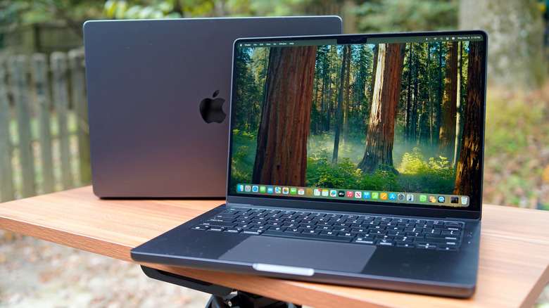 An outdoor shot of two MacBook Pros sitting back-to-back on a table.