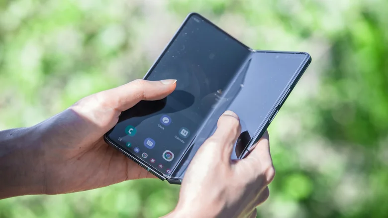A person holding a Samsung Galaxy Fold 6 outdoors.