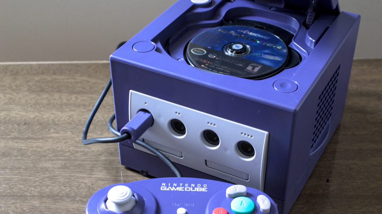 Shot of a purple GameCube with an open lid, revealing the metallic GameCube Optical Disc inside.