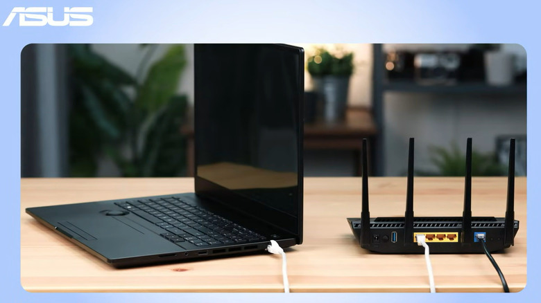 An ASUS computer is connected to a black ASUS router, which sit beside each other on a table.