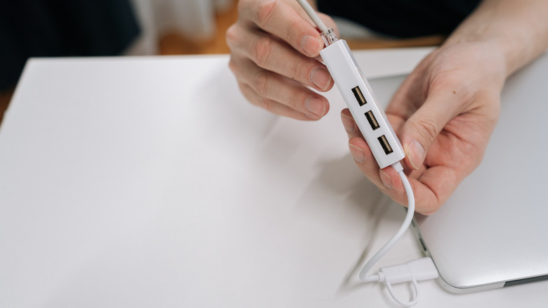 A USB-C hub plugged into a laptop. Someone is holding it to show off its ports.