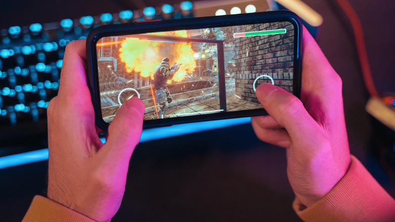 A person playing an action shooter phone game.