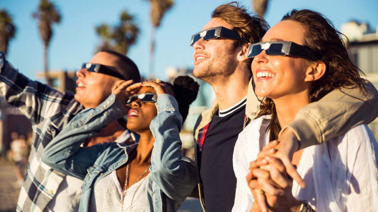 A group of friends in eclipse glasses looking at the sky which is out of frame