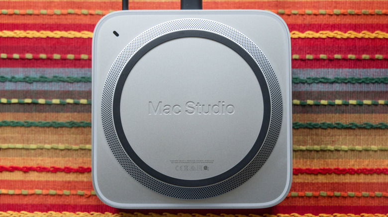A Mac Studio is shown from the bottom with the speaker grid and power light visible