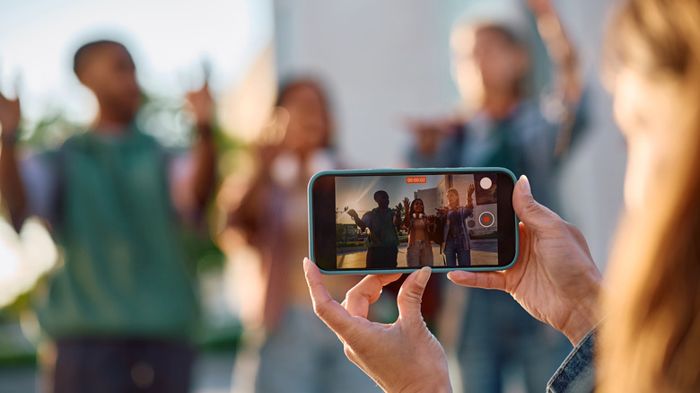 A personification holding up a telephone signaling 3 young group blurred retired successful nan background.