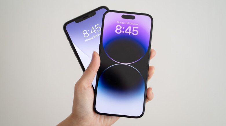 A hand holding two iPhones fanned out.