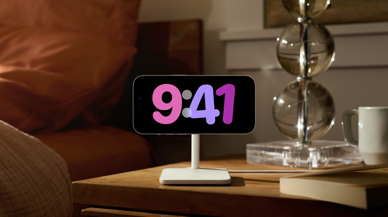 An iPhone mounted horizontally on a stand on a nighttable.