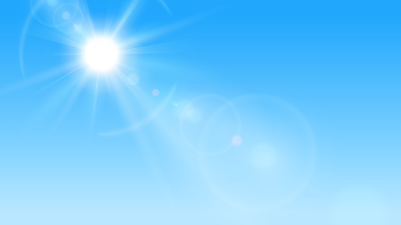 The sun in a blue sky, causing a lens flare effect.
