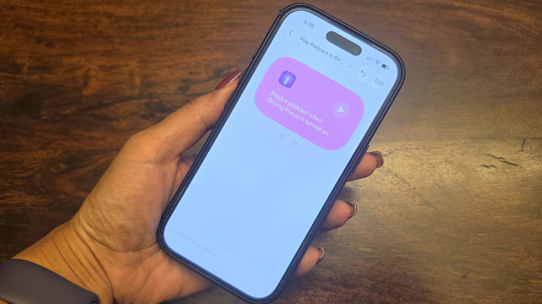 A hand holding an iPhone, showing Driving focus mode with an automation.