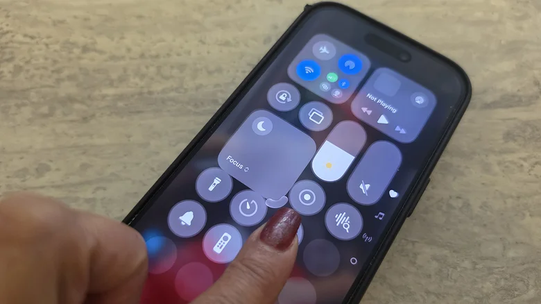 A finger dragging on the Focus mode icon in Control Center on iPhone to make it bigger.