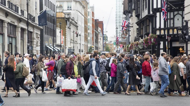 A crowded outdoor area with people walking across the street.