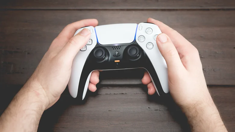 A closeup of a man holding a DualSense controller.