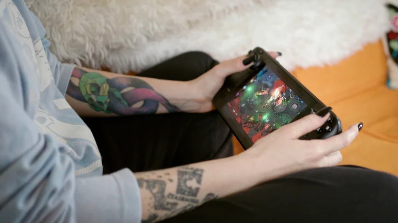 A person sitting and holding a Steam Deck.
