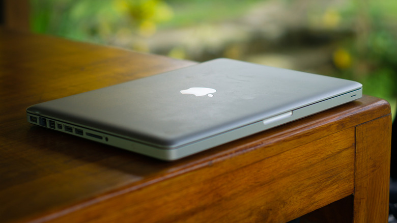 An old MacBook model sitting on a desk