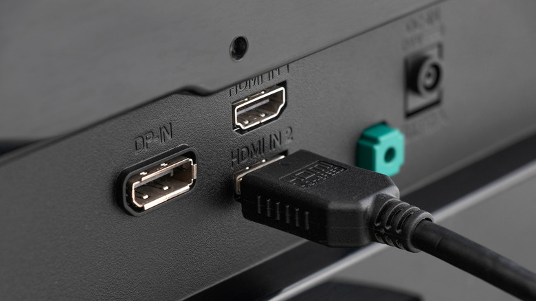 HDMI cable connected to an HDMI input on the back of a display, alongside other ports.