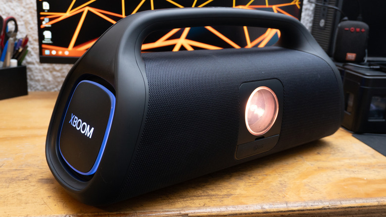 Portable LG xboom speaker on a wooden desk.