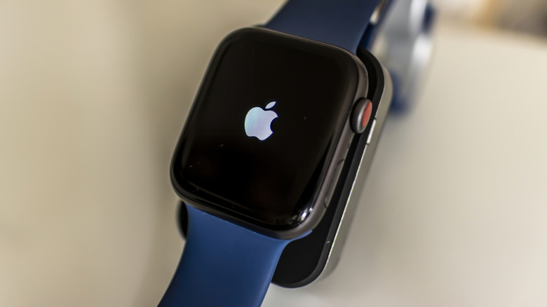 An Apple Watch showing the Apple logo while it's on a charger.