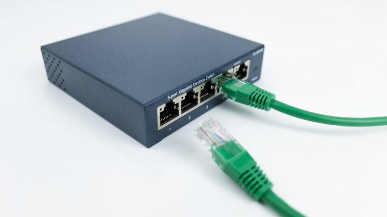 An Ethernet switch on a white background with two green network cables.