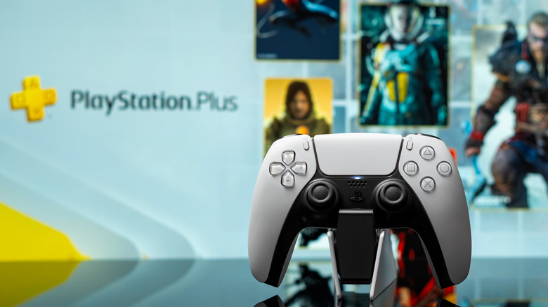 A PS5 controller in front of a TV with PlayStation Plus on it