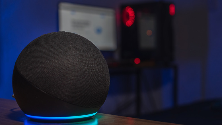 Imagem de um quarto escuro de um Amazon Echo, uma tela de computador desfocada e uma torre ao fundo.
