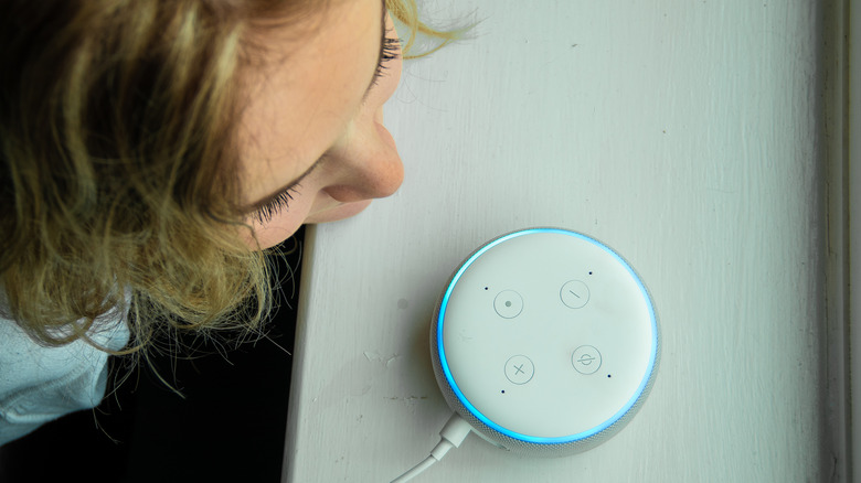 Someone leaning in to prompt Alexa on an Amazon Echo Dot device.
