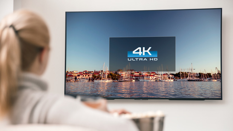 A woman looking at a TV that says "4K Ultra HD" on a background of water and boats.