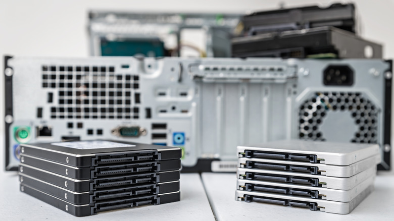 A pile of storage drives with a PC in the background.
