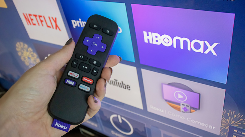 Person pointing a Roku remote control at a TV