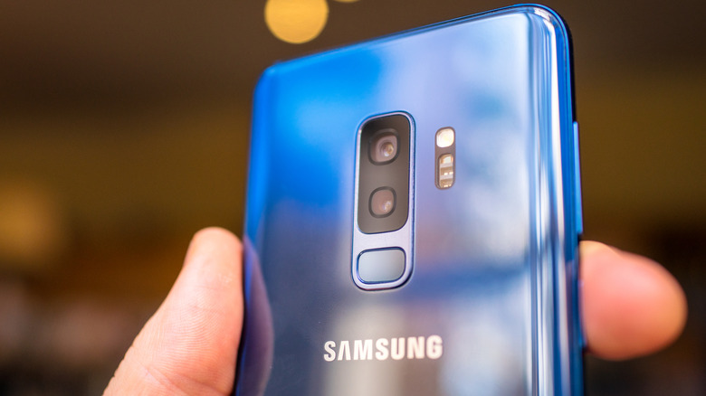 Person holding coral blue Samsung S9+.
