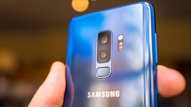 Person holding coral blue Samsung S9+.