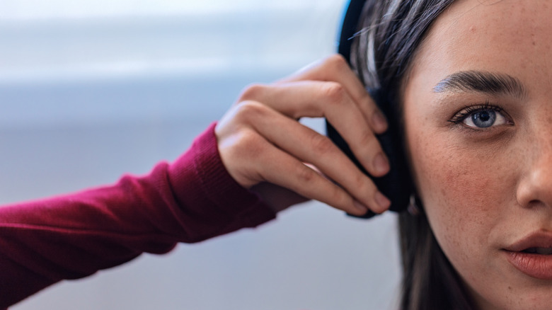 Woman adjusting volume on headphones.