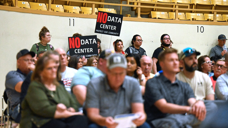 A town hall meeting where protestors display "No Data Center" signs.
