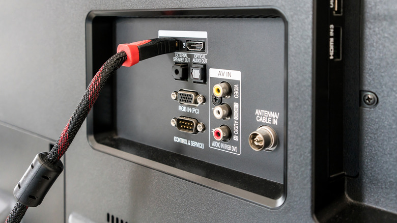 An HDMI cable, plugged into the back of a TV amongst various other ports.