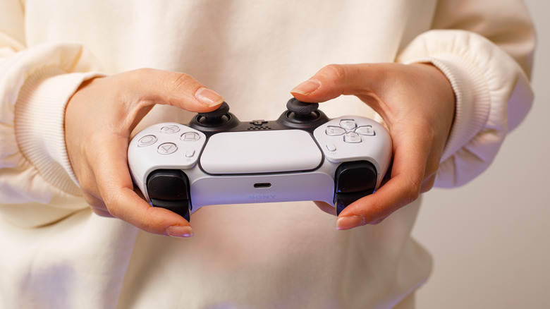 A person holding a PS5 DualSense controller