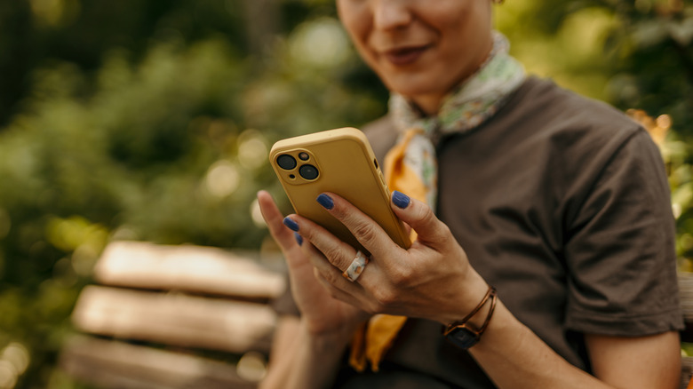 Woman on a park bench using iPhone.