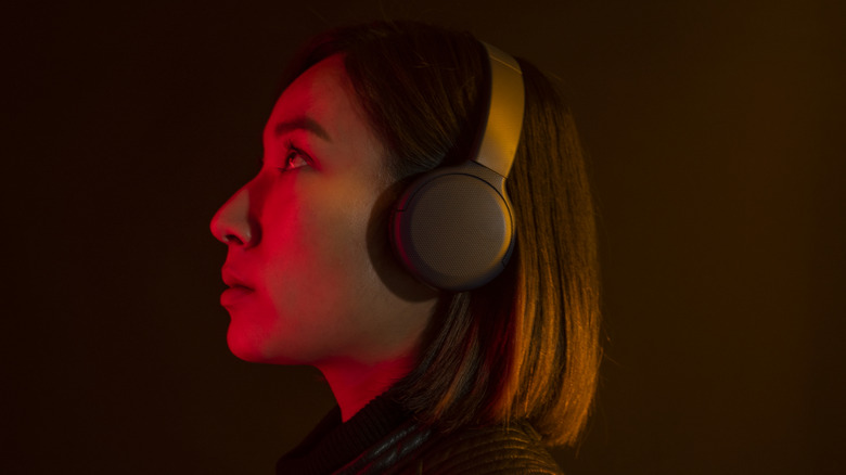 Woman wearing over-ear headphones looking up.