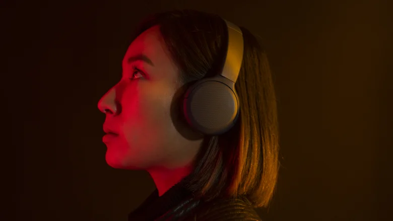 Woman wearing over-ear headphones looking up.