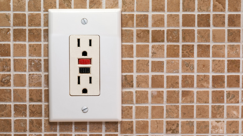 Photo of a white A/C outlet installed on a wall of small, square tan tiles.