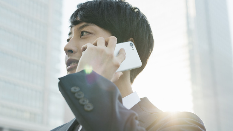 Man taking a phone call on a white Android phone.