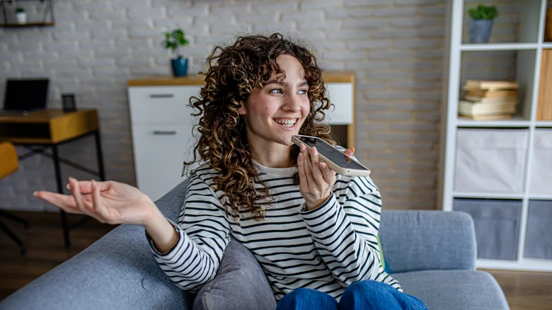 Smiling woman speaking into an iPhone.