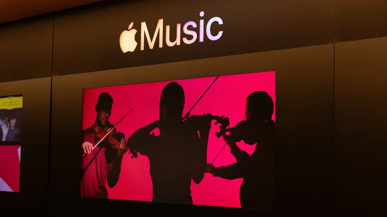 An Apple Music display with a red screen showing people playing violin.