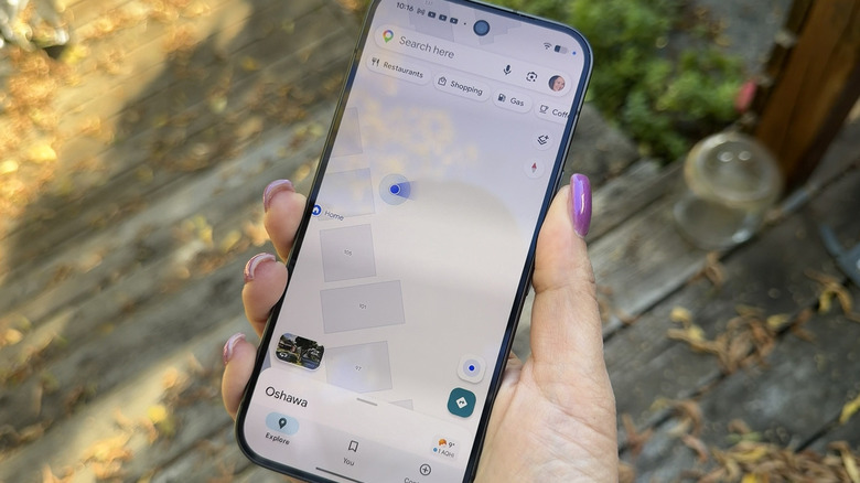 A hand holding a Google Pixel 11 Pro showing a Google Maps view with a blue dot.
